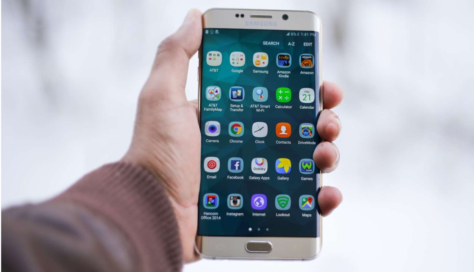 Mão segurando smartphone com apps de viagem na tela
